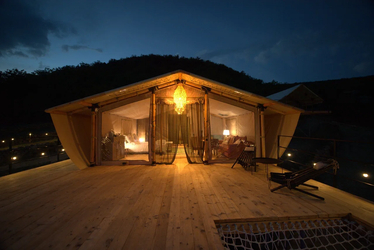 Family glampingtent bij nacht met overdekt terras